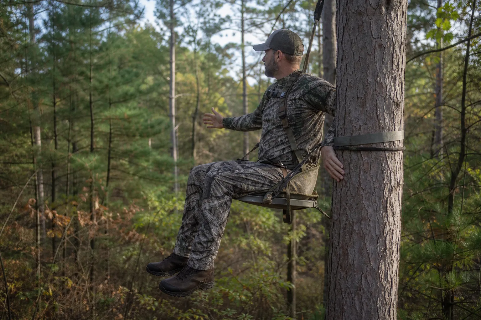 A hunter demonstrates how a saddle, bridge, tether, and lineman belt support the body on a tree.