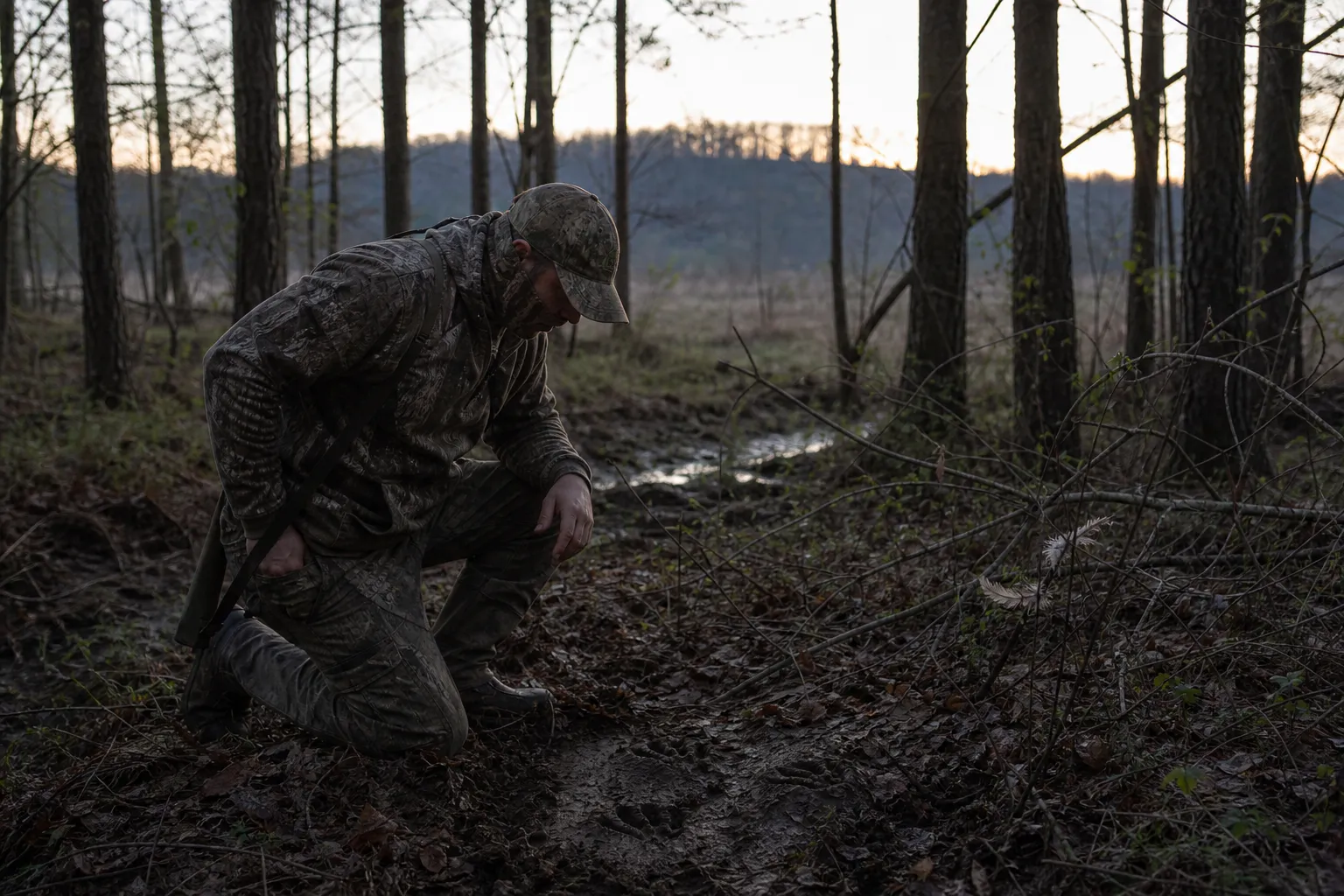 A hunter studies turkey sign in a quiet wooded area before sunrise.