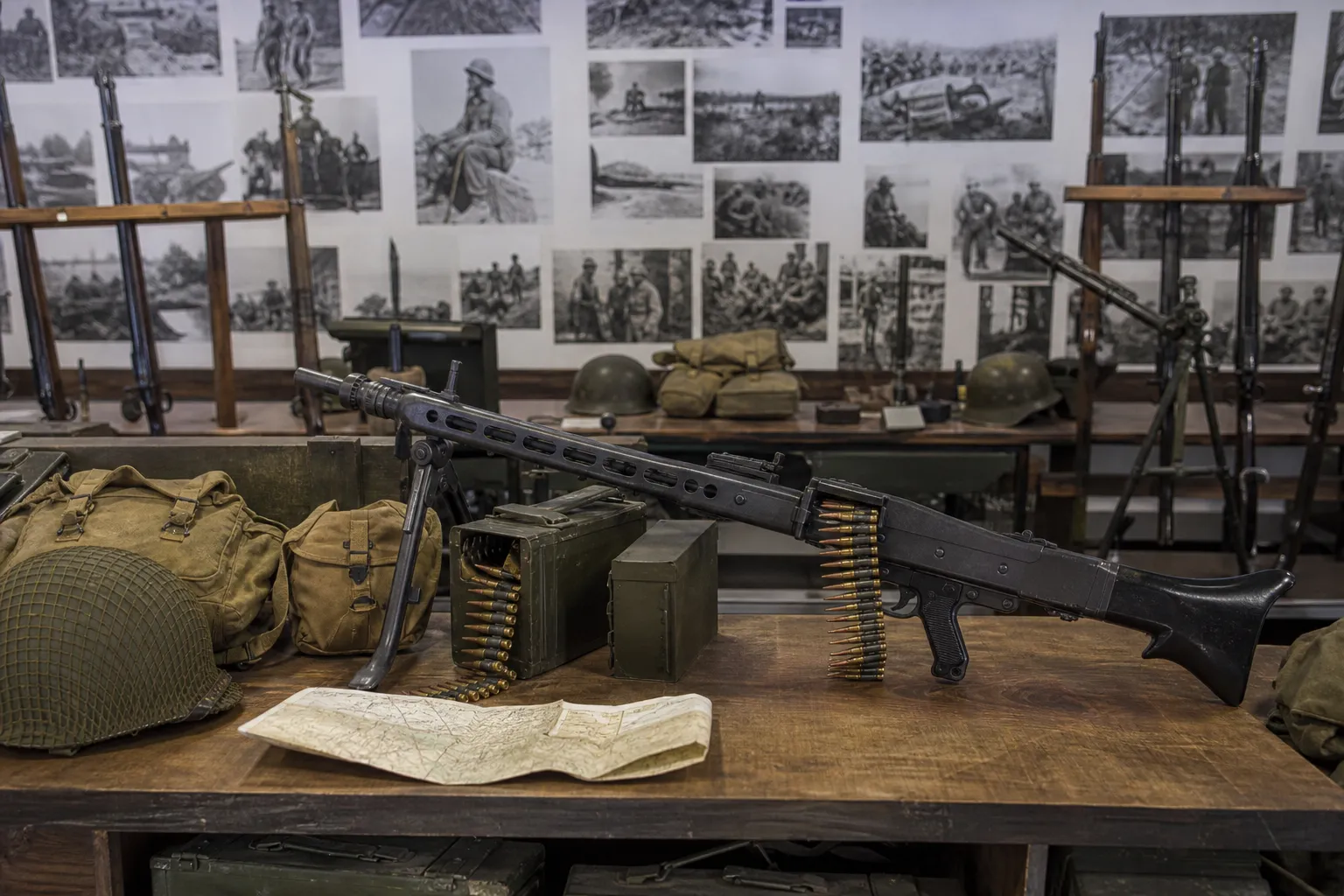 A generic belt fed squad automatic weapon displayed safely with field gear in a museum style setting.
