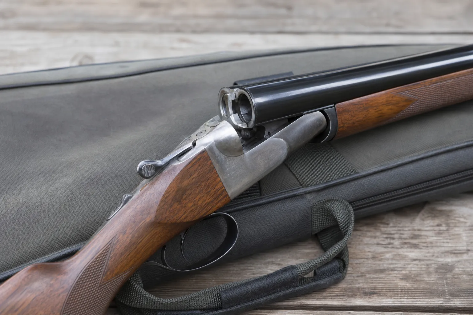 A break action shotgun is shown open with the breech exposed so the chambers can be seen.