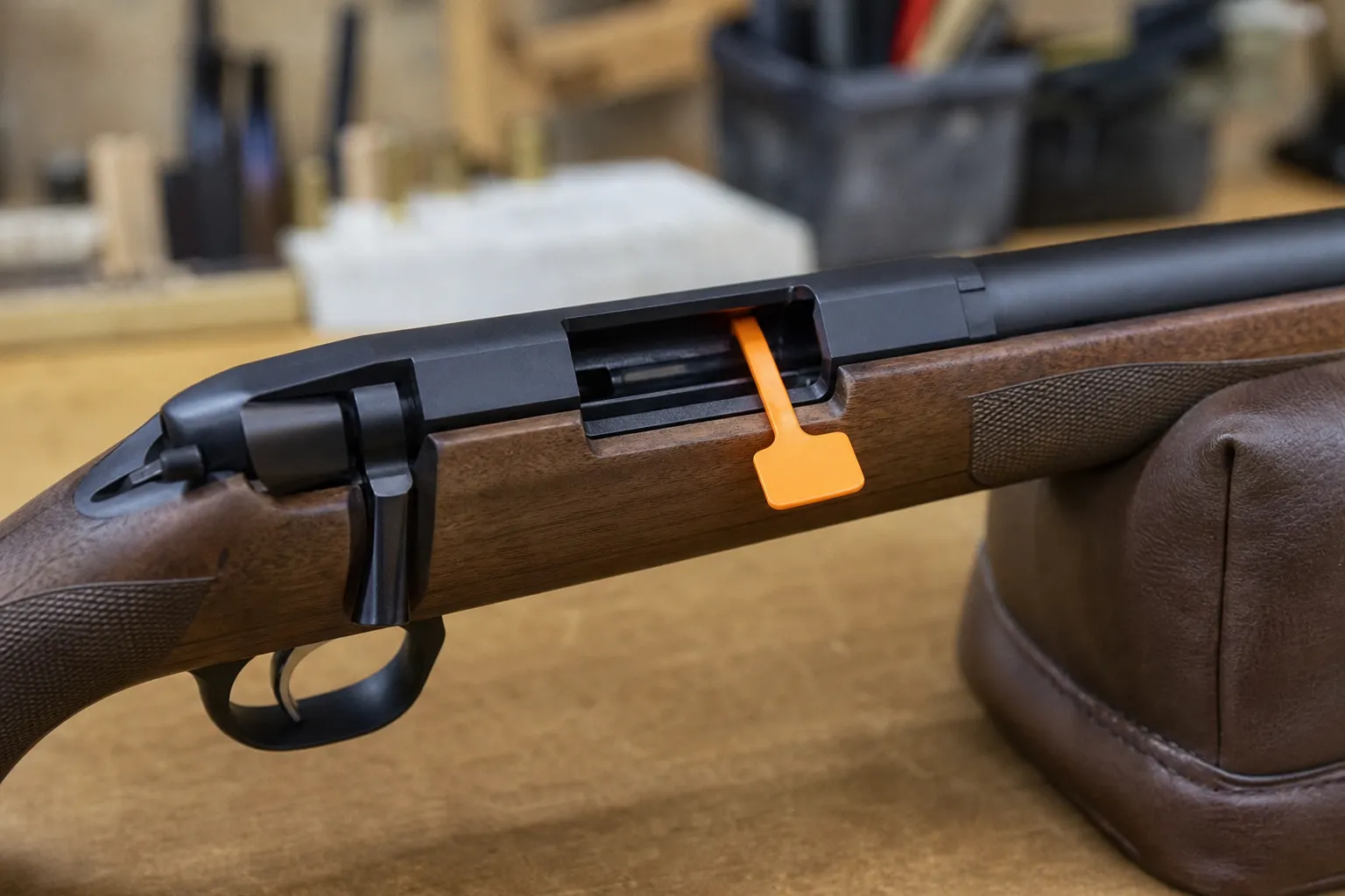 A close up of a bright orange chamber flag inserted into an open firearm action.